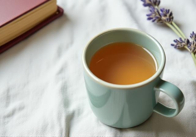 A steaming cup of herbal tea next to a notebook in the soft morning light